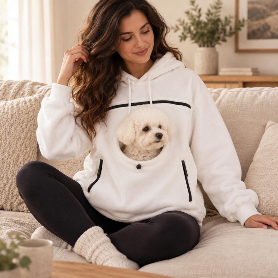 White pet carrier hoodie worn on a couch, small white dog riding in the front pouch