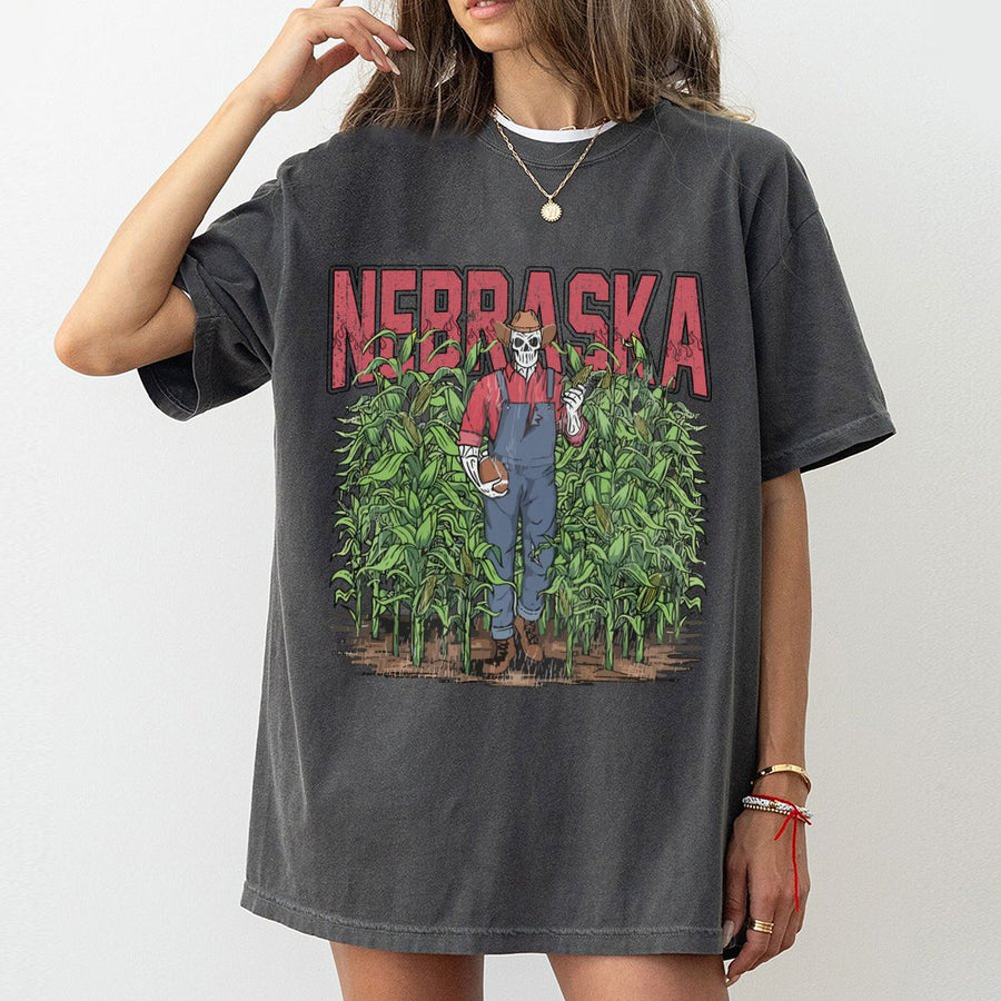 Nebraska With A Skeleton Dressed As A Farmer In Overalls Holding A Football And An Ear Of Corn While Standing In A Cornfield T-Shirt