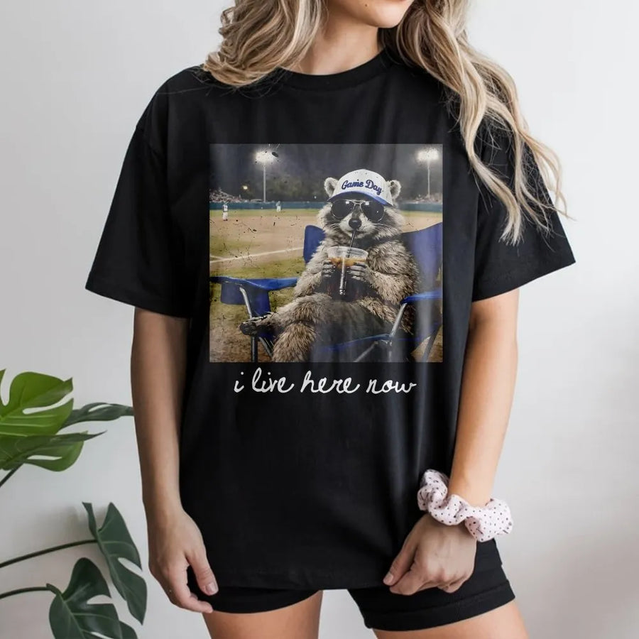 I Live Here Now Raccoon Shirt | Funny Travel Ball Parent Life Meme | Soft 100% Cotton Tee | Gift for Baseball Mom or Softball Dad