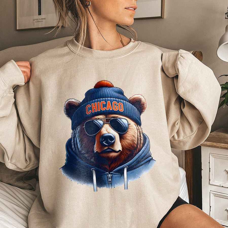 Chicago Bear Wearing Sunglasses, A Blue Beanie With An Orange Pom-Pom, And A Blue Sweatshirt