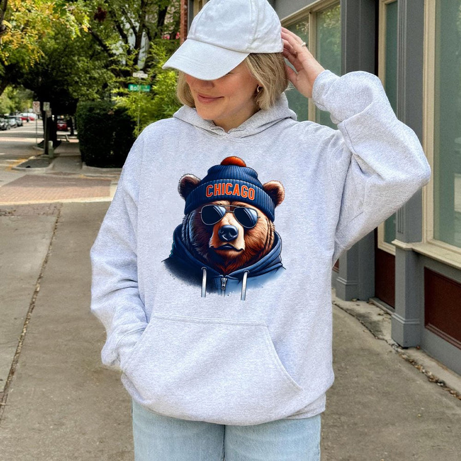 Chicago Bear Wearing Sunglasses, A Blue Beanie With An Orange Pom-Pom, And A Blue Hoodie