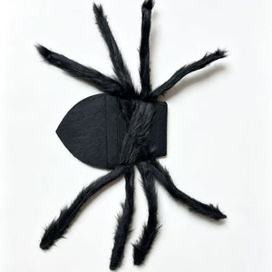 Black smooth-bodied plush spider with eight furry legs, laid flat