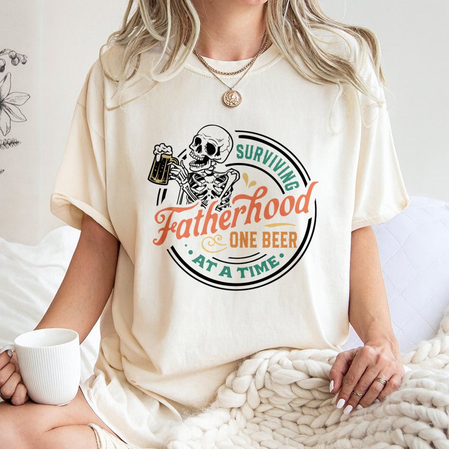 Surviving Fatherhood One Beer At A Time T-Shirt | Funny Skeleton Beer Graphic | Premium 100% Cotton Tee | Perfect Father's Day 2026 Gift For Dad