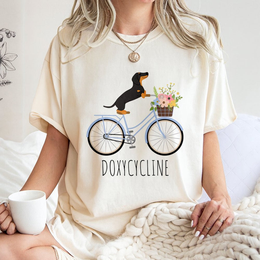 Dachshund Bicycle T-Shirt | Doxycycline Pharmacy Pun Graphic | Premium Cotton Unisex Tee | Gift for Pharmacists Pharmacy Techs