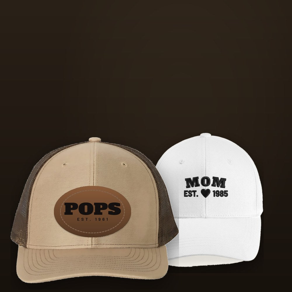 Two custom hats side by side: a khaki leather patch cap engraved POPS and a white cap embroidered MOM