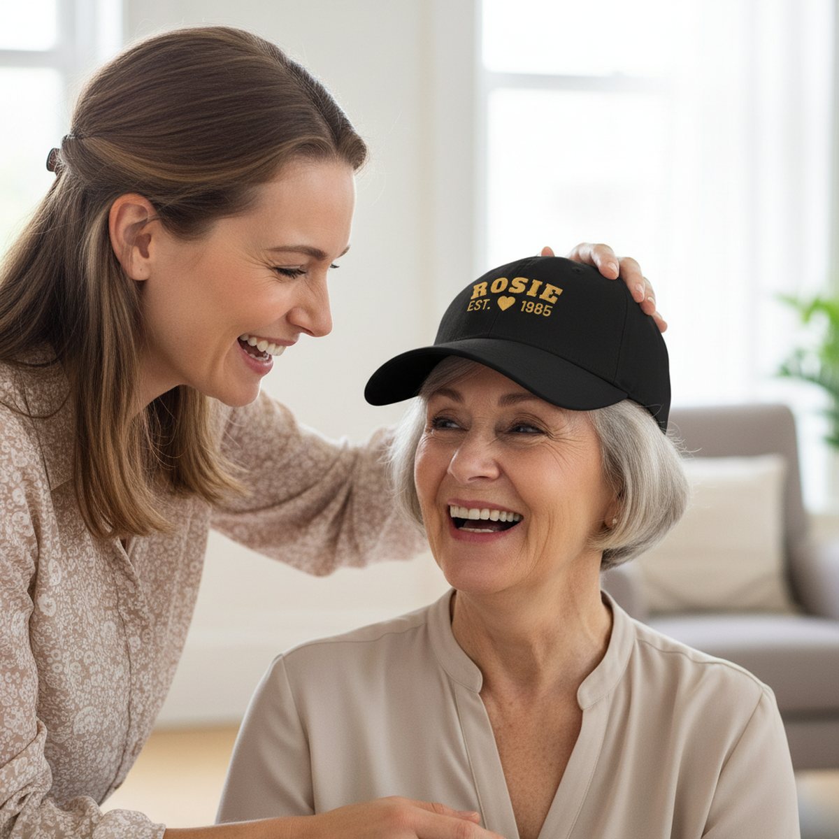 A daughter placing a black embroidered cap on her laughing mother
