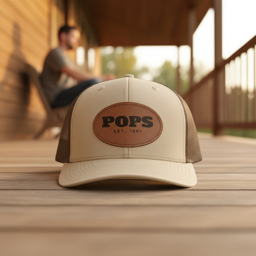 Khaki trucker cap with a laser-engraved leather patch reading POPS EST. 1961